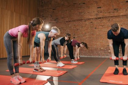 Fitness group performing exercises with dumbbells in a modern yoga studio setting.