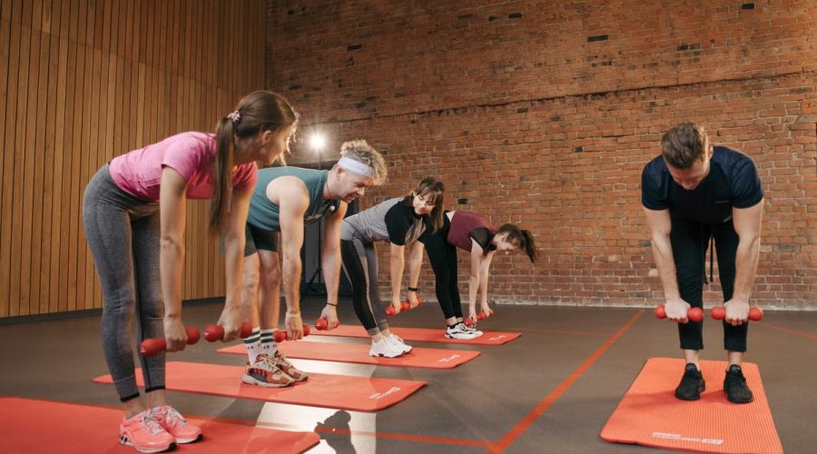 Fitness group performing exercises with dumbbells in a modern yoga studio setting.