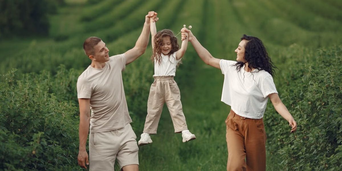 Joyful family moment in a green field during summer, capturing love and playfulness.