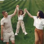 Joyful family moment in a green field during summer, capturing love and playfulness.