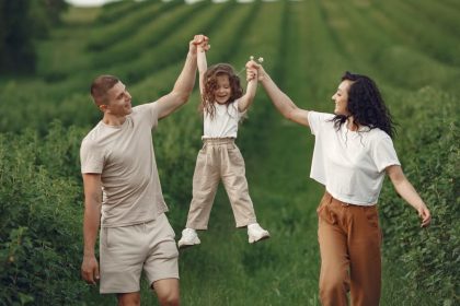 Joyful family moment in a green field during summer, capturing love and playfulness.